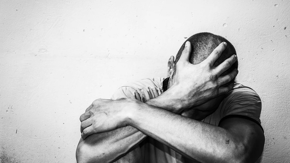 causes of hair loss, man bent down holding his head in despair